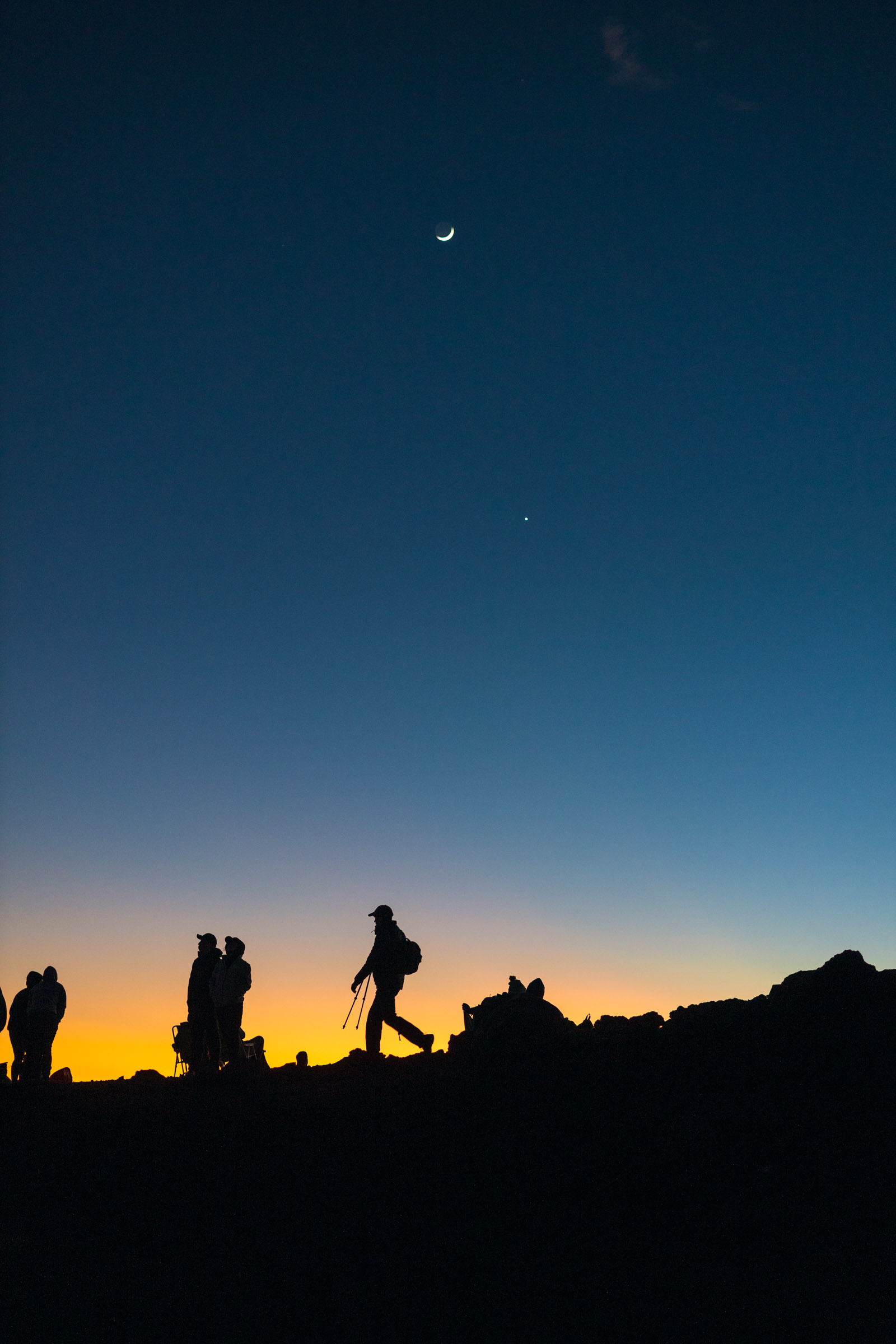 Hikers silhouetted in front of the moon
